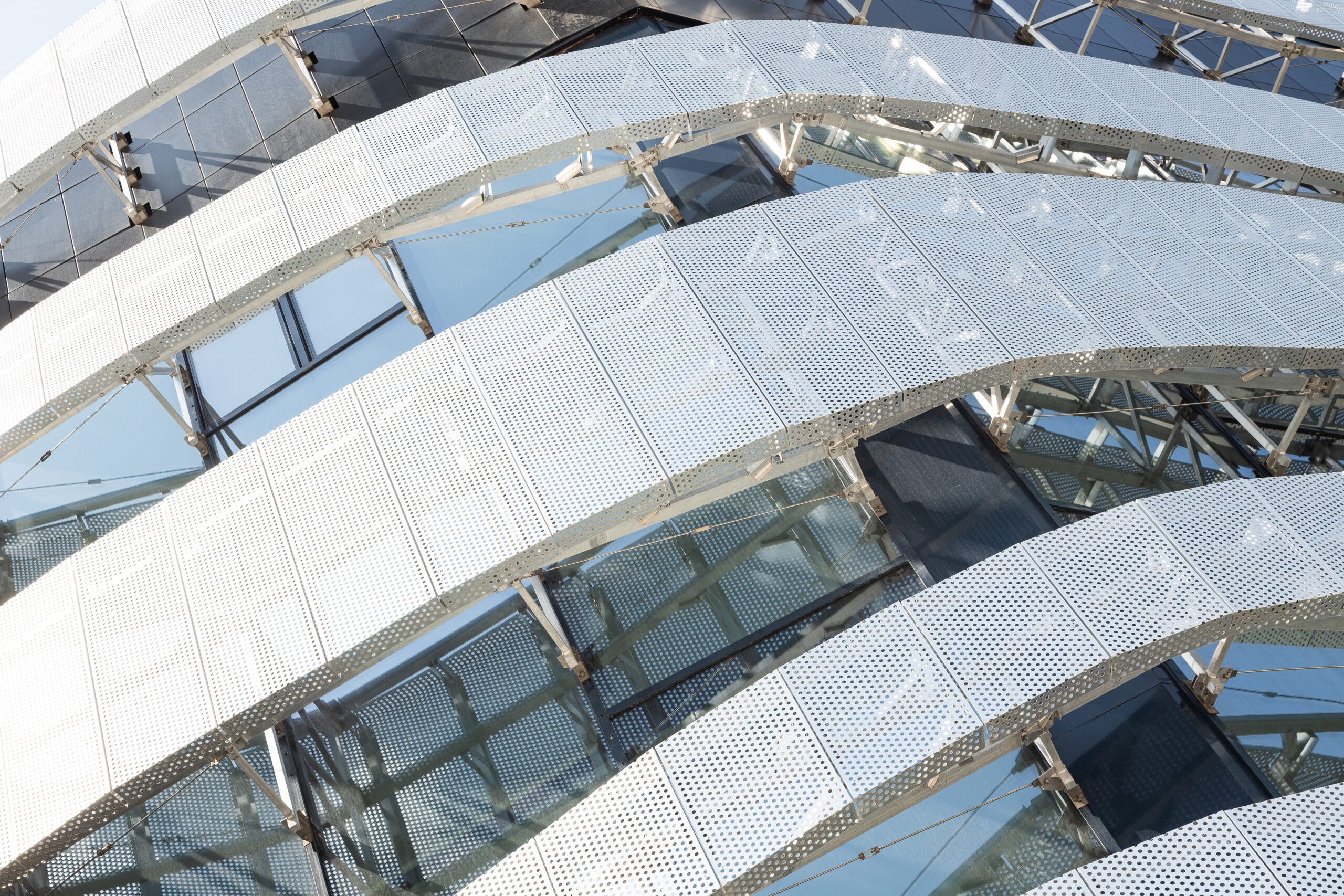 Perforated aluminum screen panels with round-hole pattern on a building perimeter